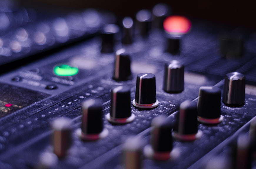 Close-up of audio mixing console knobs and buttons