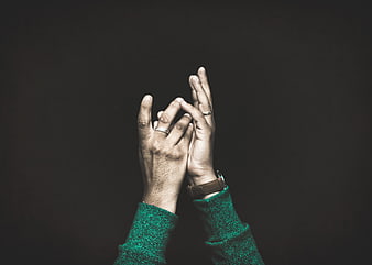 Hands clasped in prayer with rings and green sweater
