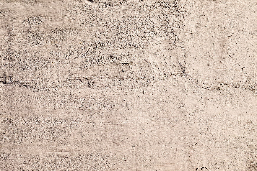 Textured beige concrete wall background with cracks and rough surface