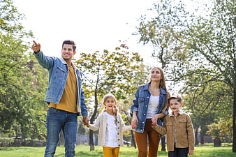 Happy family of four walking and pointing in a sunny park