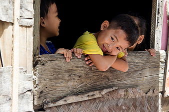 Smiling Asian Child Peeking From Weathered Wooden Window Frame