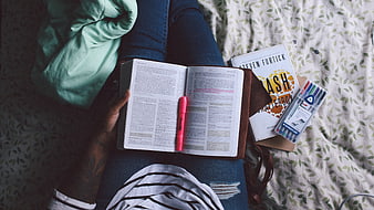Top View of Person Reading Bible with Highlighters on Bed