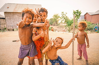 Group of smiling Cambodian children giving thumbs up in a rural village