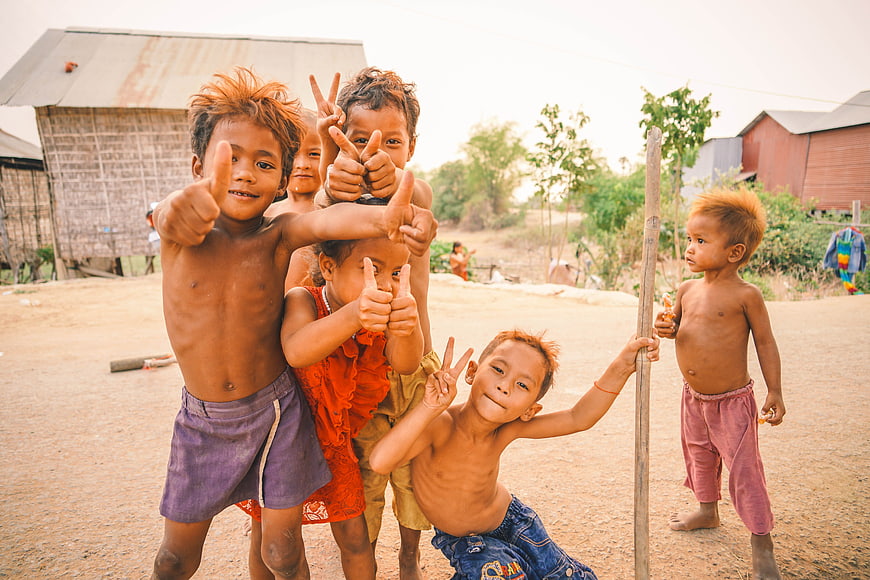 Group of smiling Cambodian children giving thumbs up in a rural village
