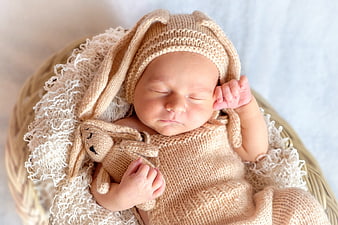 Sleeping newborn baby in knitted bunny costume in basket