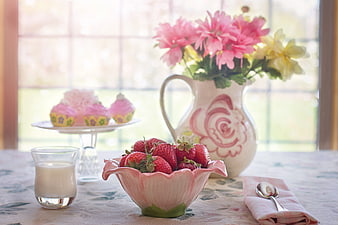 Fresh strawberries, milk, and cupcakes on a floral table