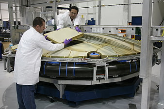 Engineers installing foam insulation on spacecraft component