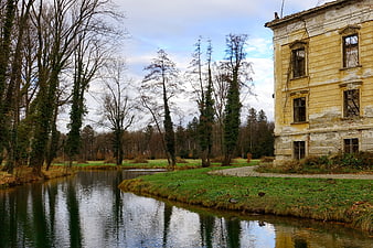 Abandoned yellow manor house by a river in autumn