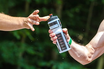 Athlete hands exchanging water bottle during outdoor sports