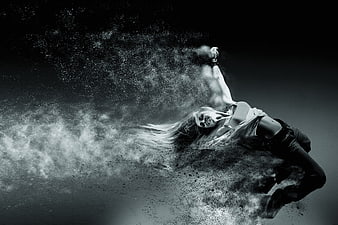 Woman dissolving into particles in dramatic black and white motion