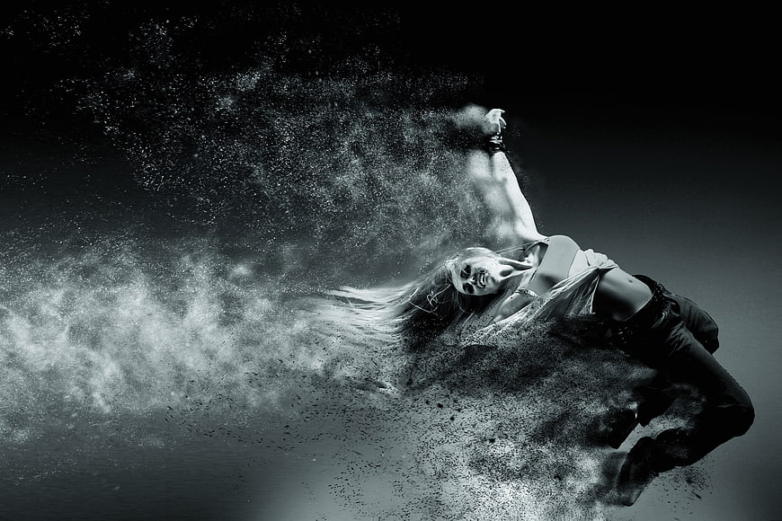 Woman dissolving into particles in dramatic black and white motion