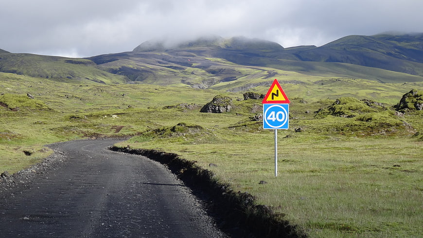 Winding gravel road in Icelandic highlands with speed limit sign
