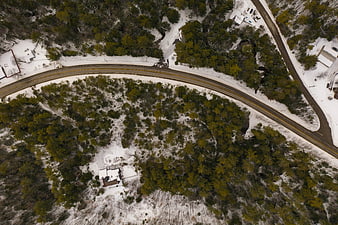 Aerial View of Winding Road Through Snowy Forest