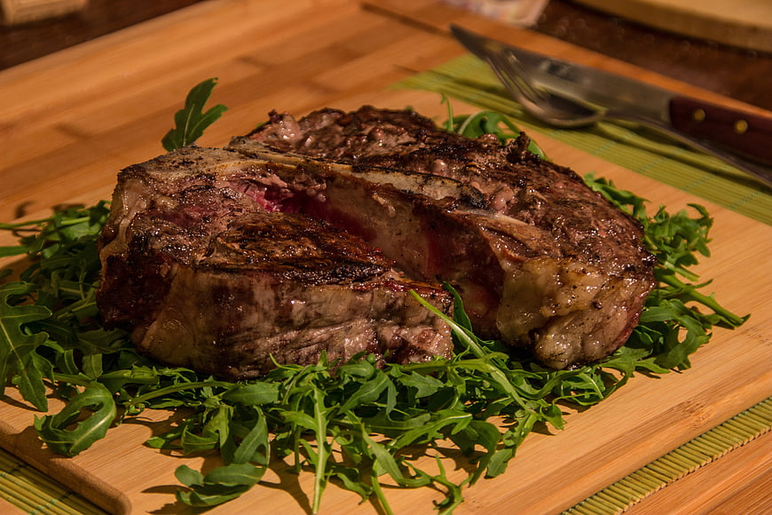 Grilled Ribeye Steak with Arugula on Wooden Board