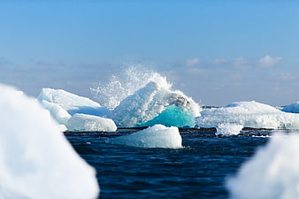 Glacial Iceberg Splashing in Blue Ocean Water