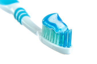 Close-up of blue toothbrush with toothpaste on white background