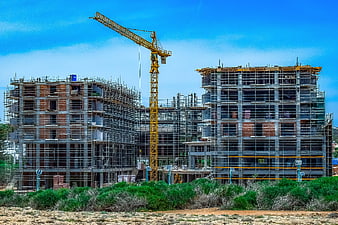 Multi-story residential building under construction with yellow tower crane