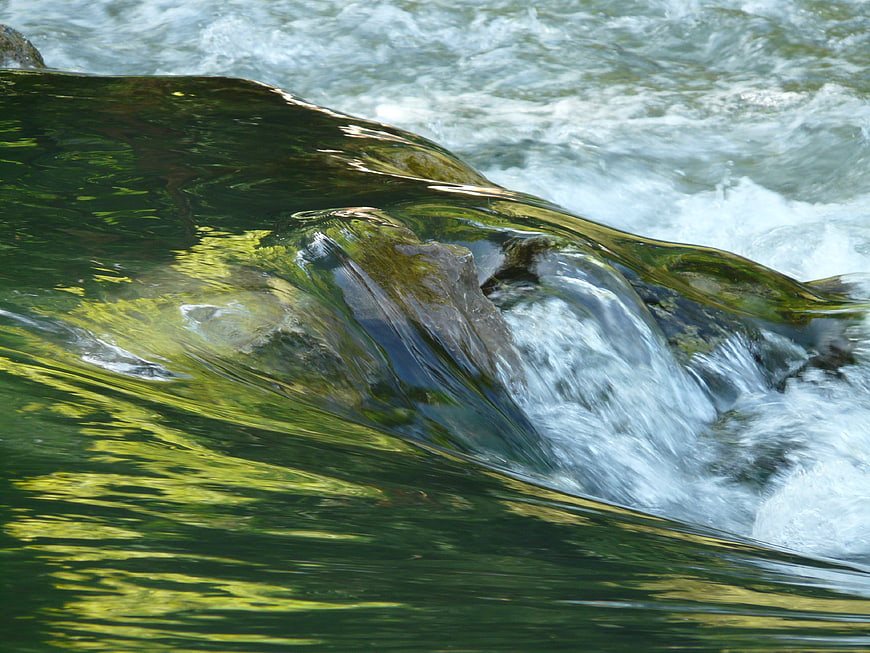 Flowing River Water Over Mossy Rocks in Nature