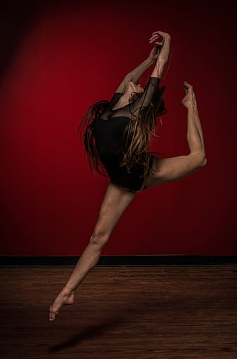 Female Dancer Performing Dynamic Leap Against Red Studio Background