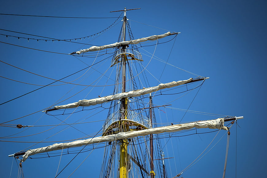 Tall ship mast and rigging against clear blue sky
