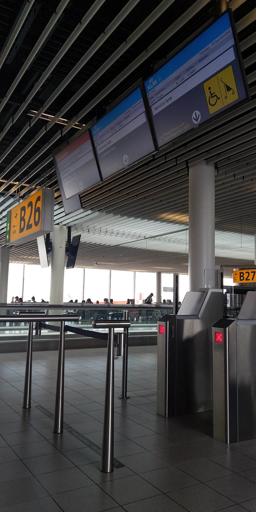 Empty airport gate B26 with digital flight information screens