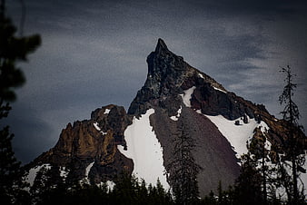 Dramatic Snowy Mountain Peak with Dark Forest Foreground