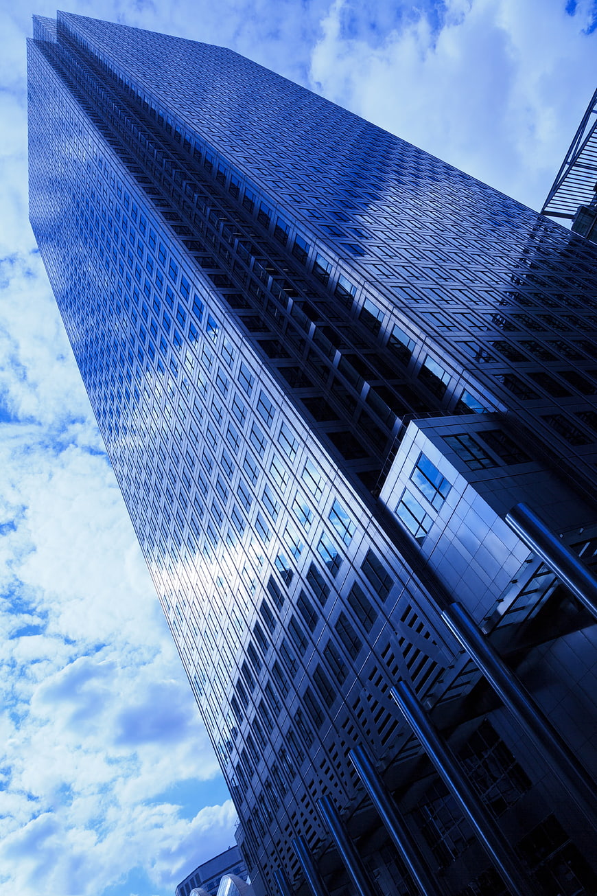 Low angle view of modern blue glass skyscraper against sky