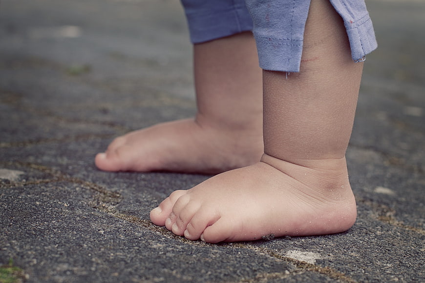 Close-up of bare toddler feet standing on pavement