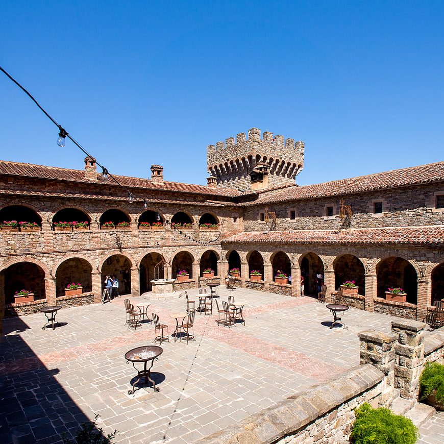 Sunlit stone courtyard of a medieval castle with arches and blue sky