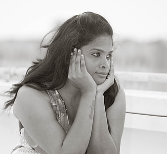 Black and white portrait of a sad young woman resting her face on her hands