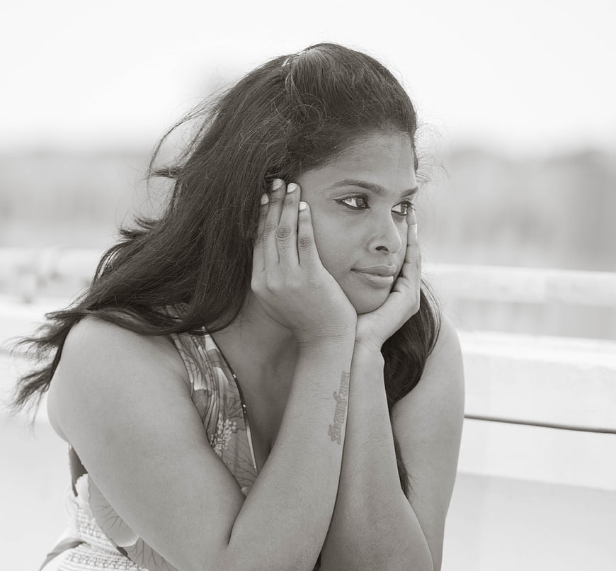 Black and white portrait of a sad young woman resting her face on her hands
