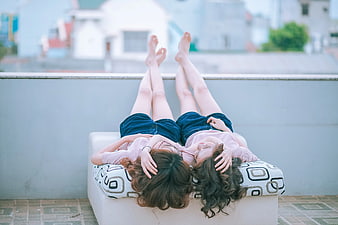 Two women relaxing on rooftop sofa with legs up