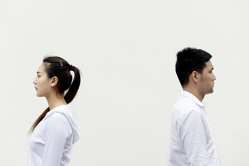 Man and woman standing back to back in white shirts