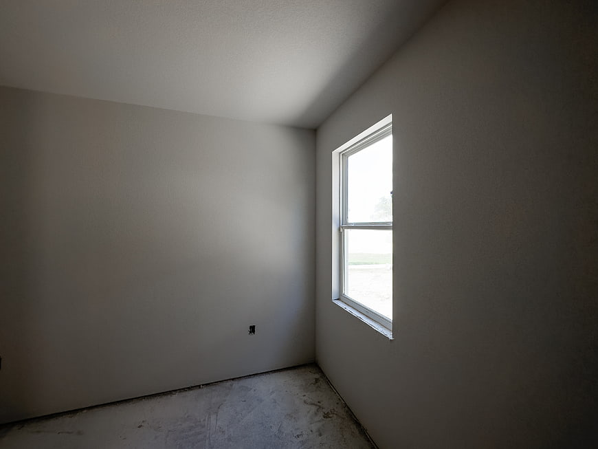 Empty unfinished room with window and concrete floor
