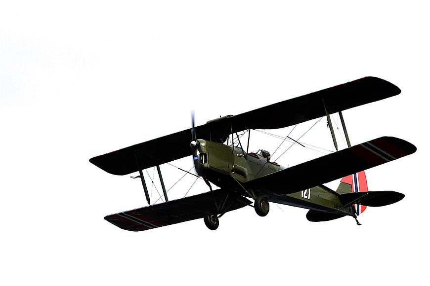 Vintage Military Biplane in Flight Against White Sky