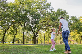 Father and daughter playing together in a sunny park