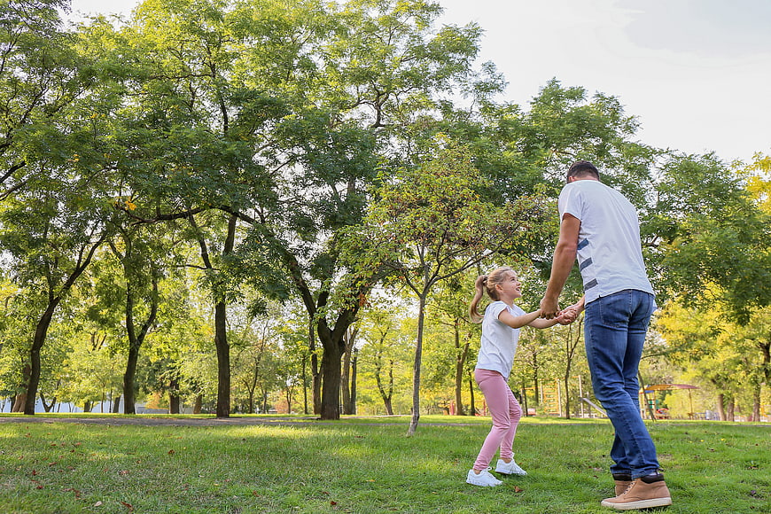 Father and daughter playing together in a sunny park