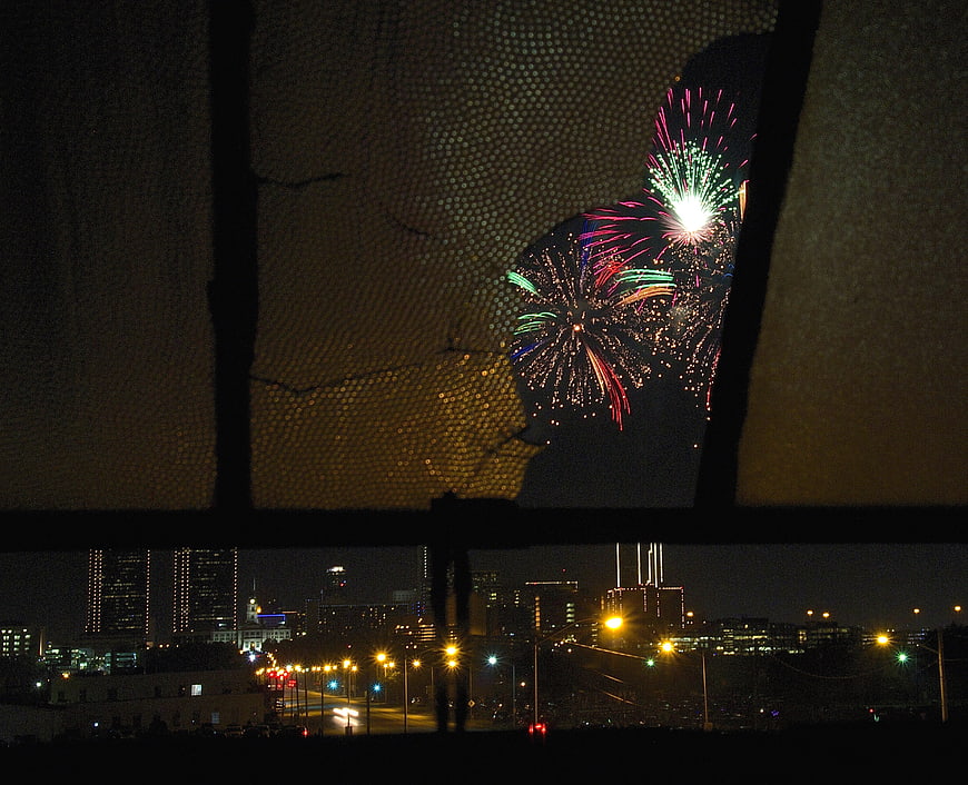 Fireworks Viewed Through Broken Window Over City Skyline