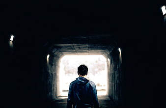 Man Walking Through Dark Tunnel Towards Light