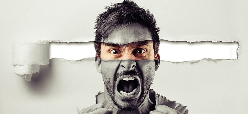 Angry man screaming through torn paper strip