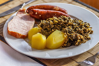 Traditional German meal with Kasslerbraten, sausages, potatoes, and kale