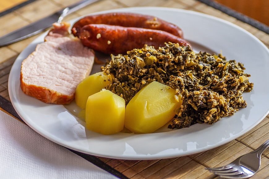 Traditional German meal with Kasslerbraten, sausages, potatoes, and kale