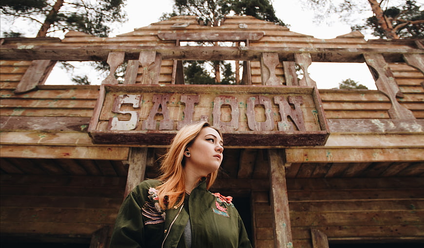 Woman standing in front of rustic wooden saloon sign