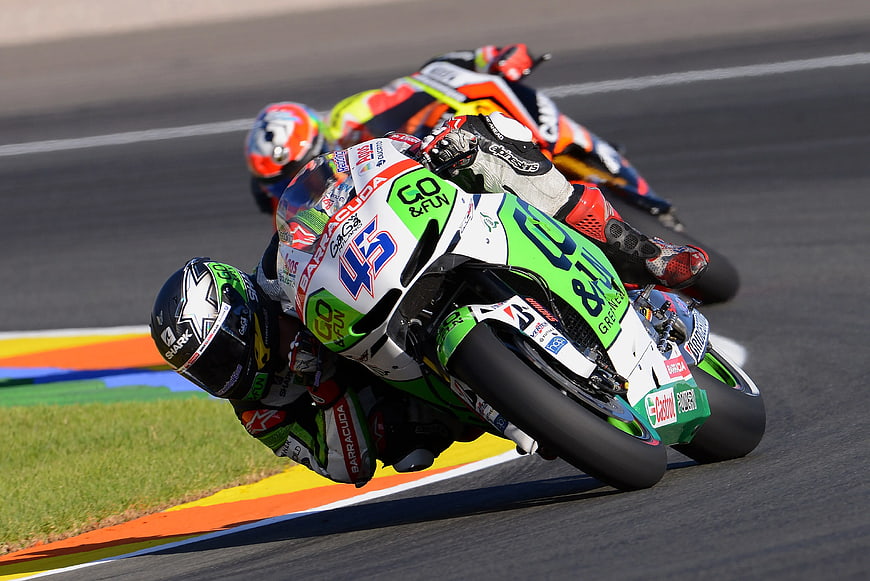 Motorcycle racers leaning into a sharp turn on a race track