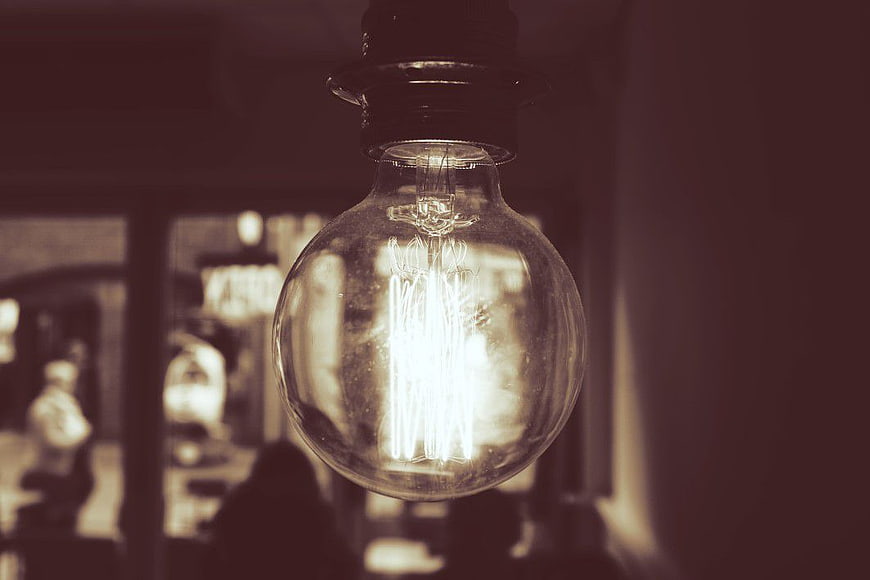 Vintage Edison Light Bulb Hanging in Dim Cafe Interior
