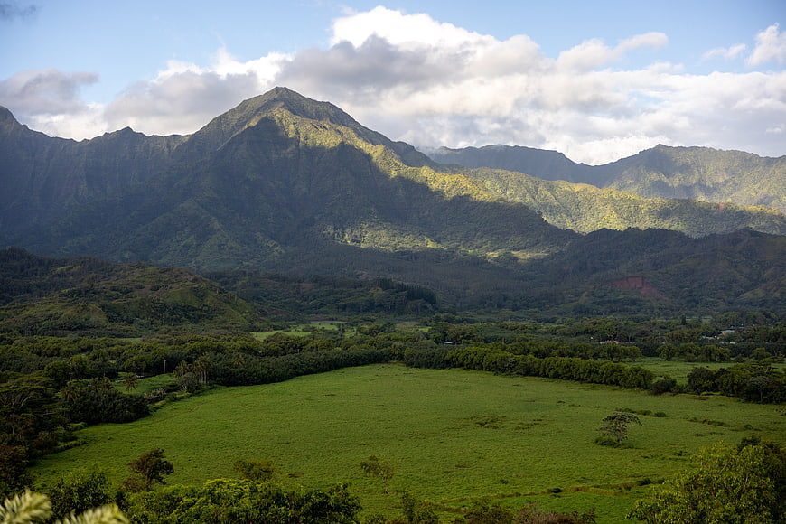 Lush Green Valley with Majestic Mountain Peaks and Clouds