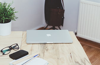 Minimalist wooden desk with laptop, glasses, and notebook