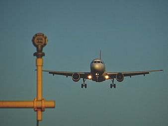 Commercial Airplane Landing with Landing Lights Against Blue Sky
