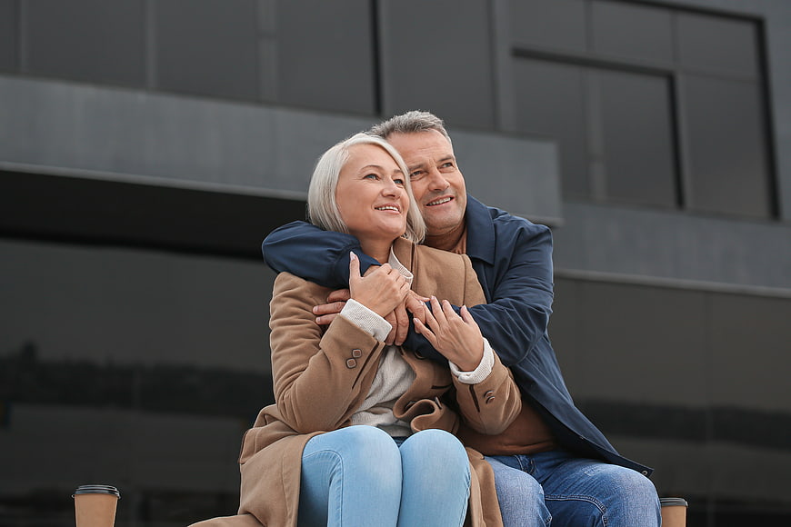 Happy senior couple embracing outdoors with coffee