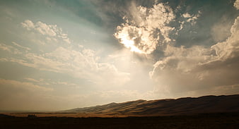 Dramatic Sun Rays Breaking Through Clouds Over Desert Dunes